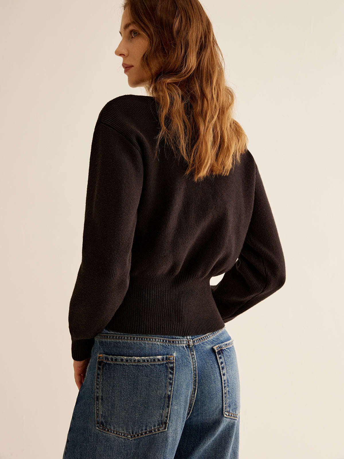 Adele black deep-V cardigan worn open over jeans, angled view