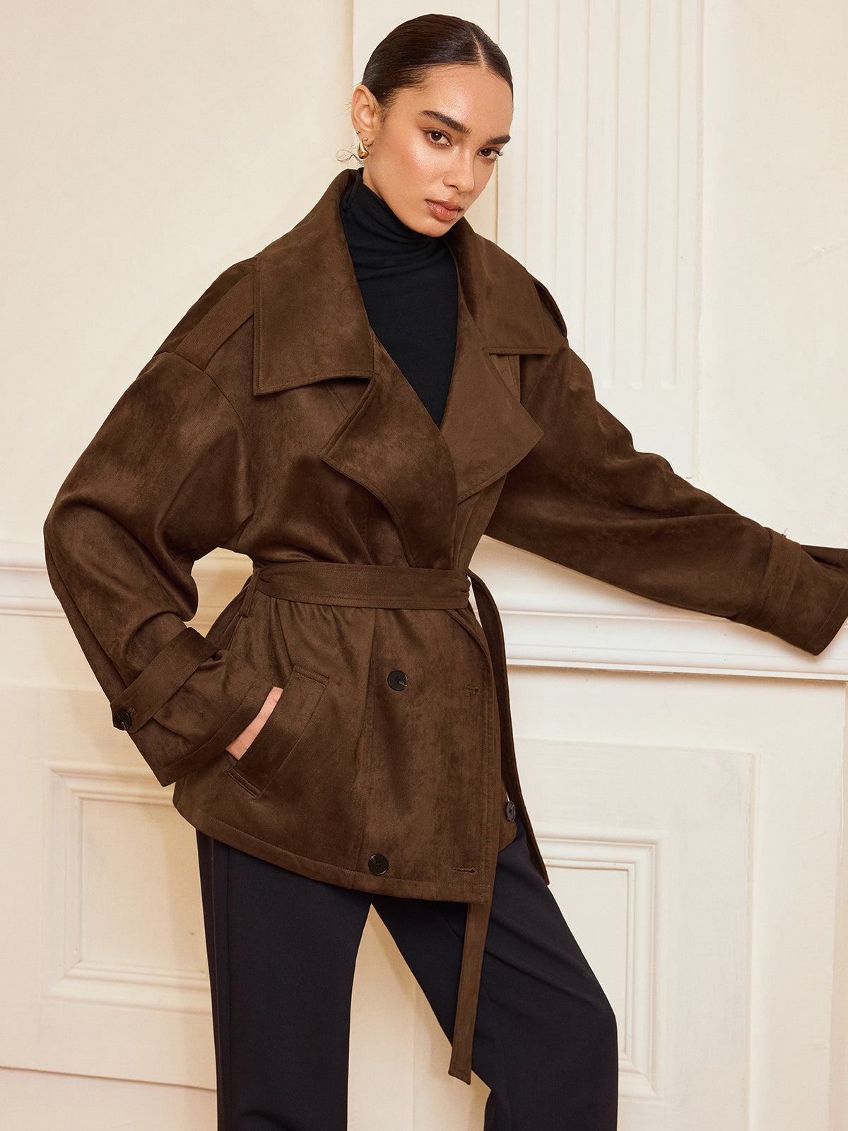 Bernadette brown belted coat worn open over a black roll neck