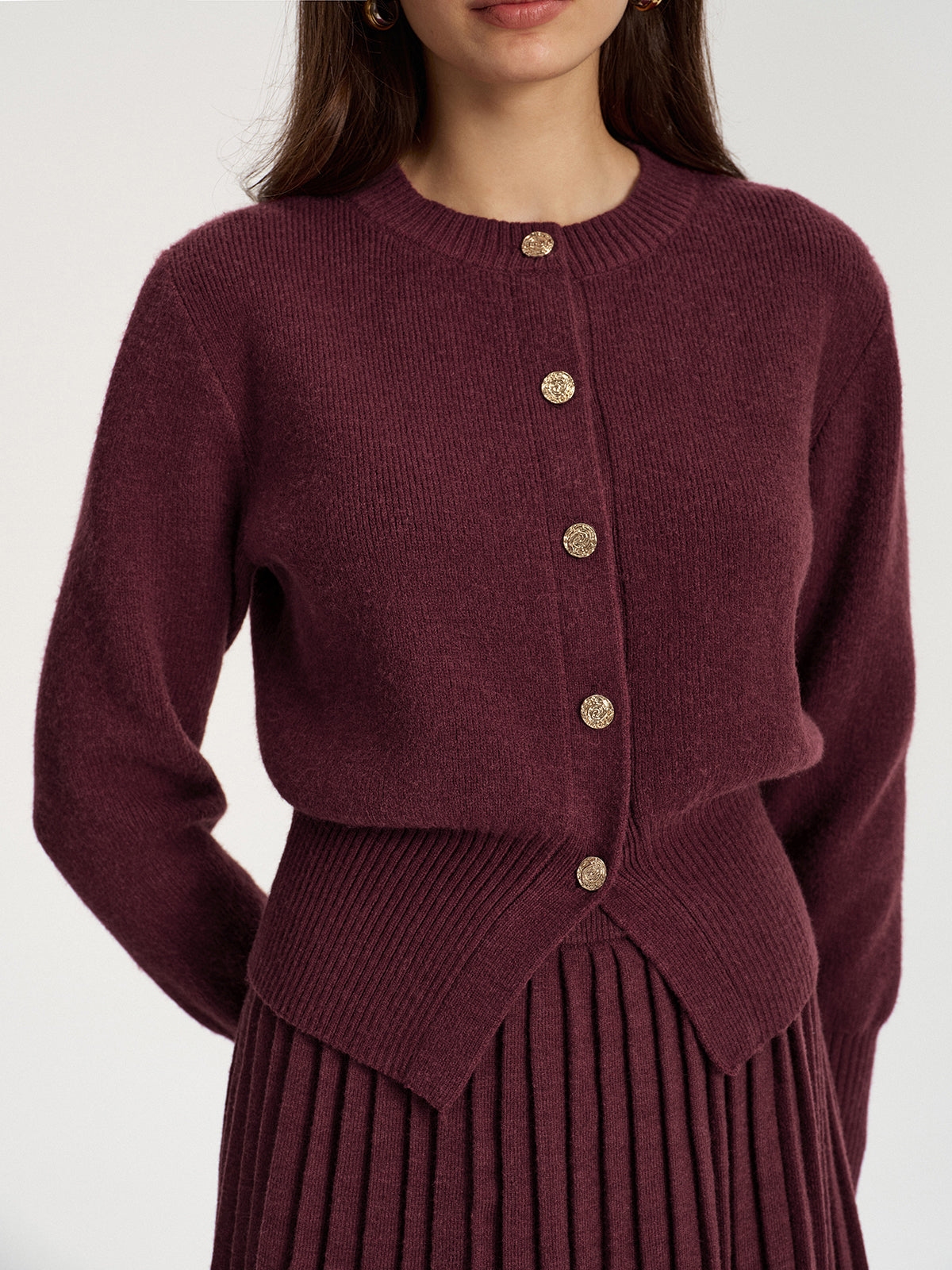 Close view of the gold-tone buttons on the burgundy round-neck cardigan