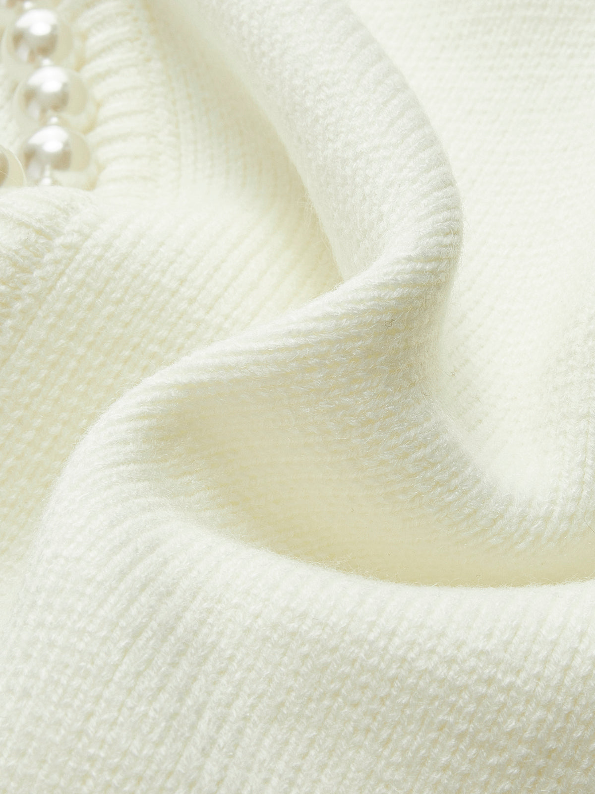 Detail of the cream knit texture and pearl edging