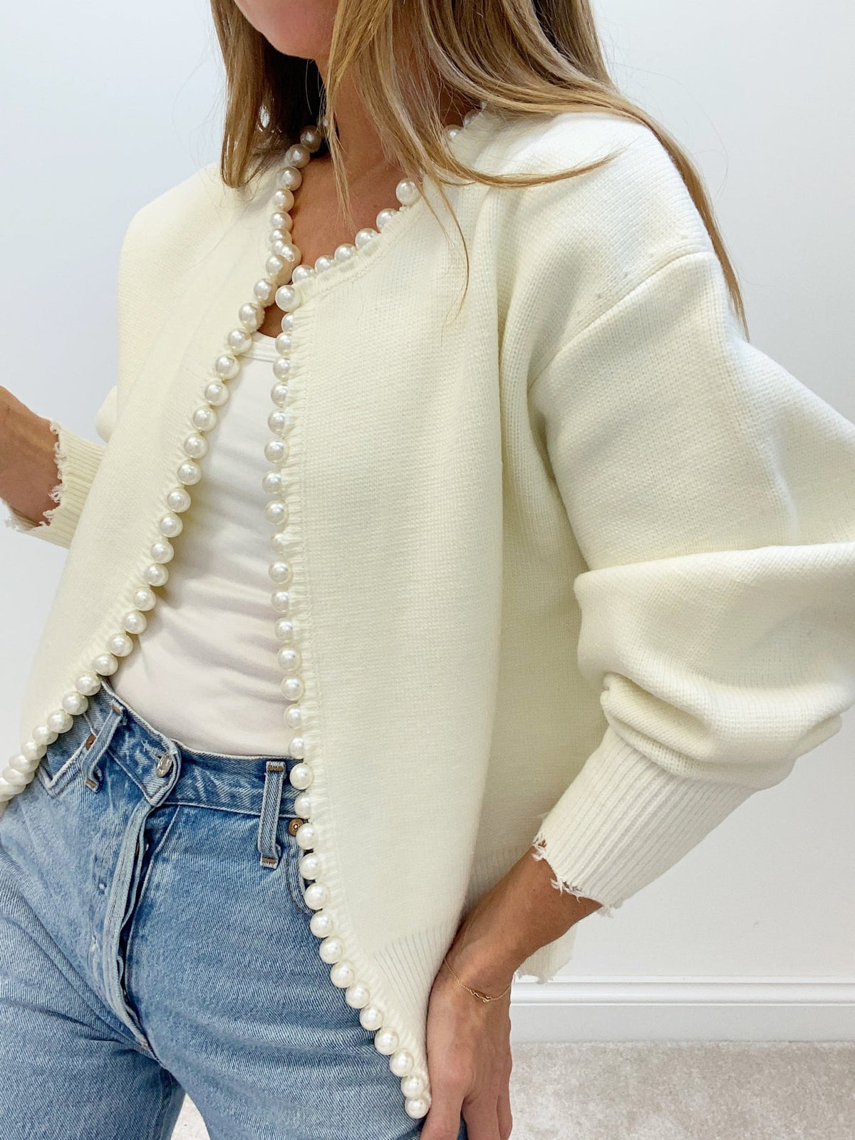 Cream pearl-trim cardigan worn open over a white top, front view