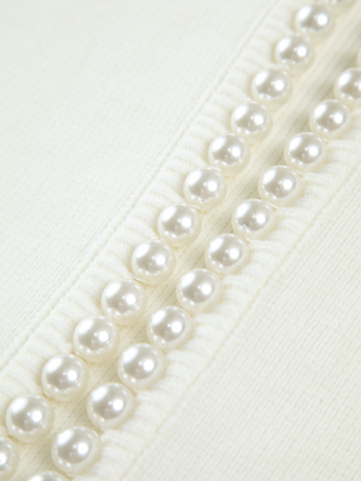 Close-up of the pearl bead trim running along the cardigan's front edge