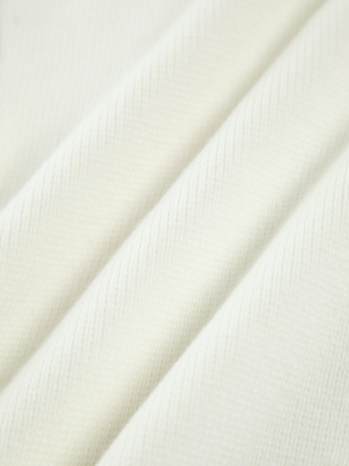 Close-up of the cream knit fabric of the pearl-trim cardigan