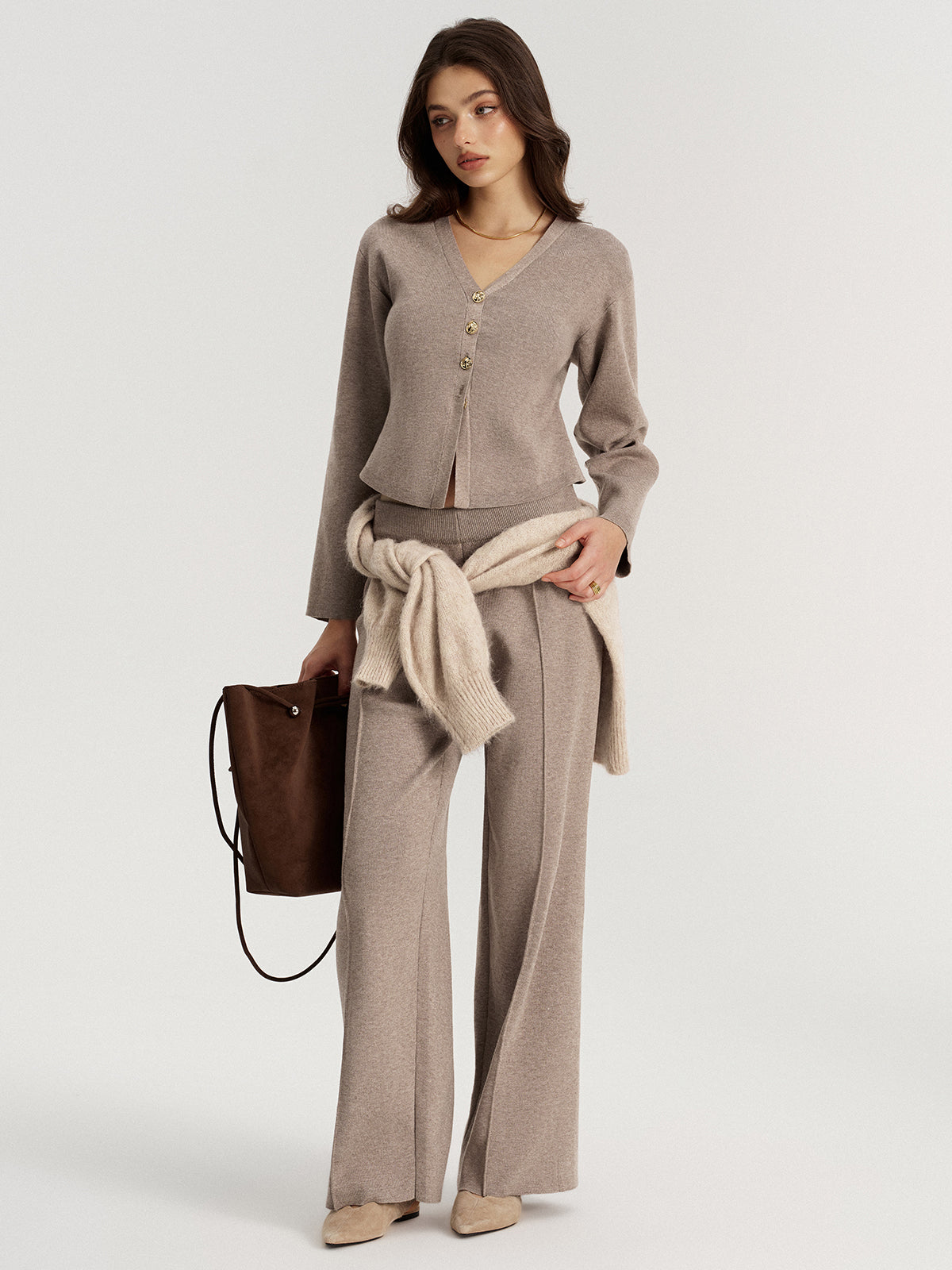 Full-length view of the taupe V-neck cardigan styled with knit trousers