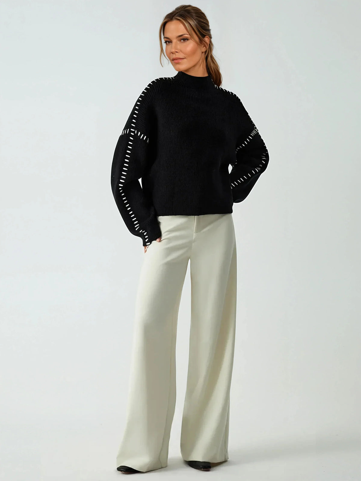 Clemence black oversized mock-neck sweater worn with wide-leg trousers, full-length view