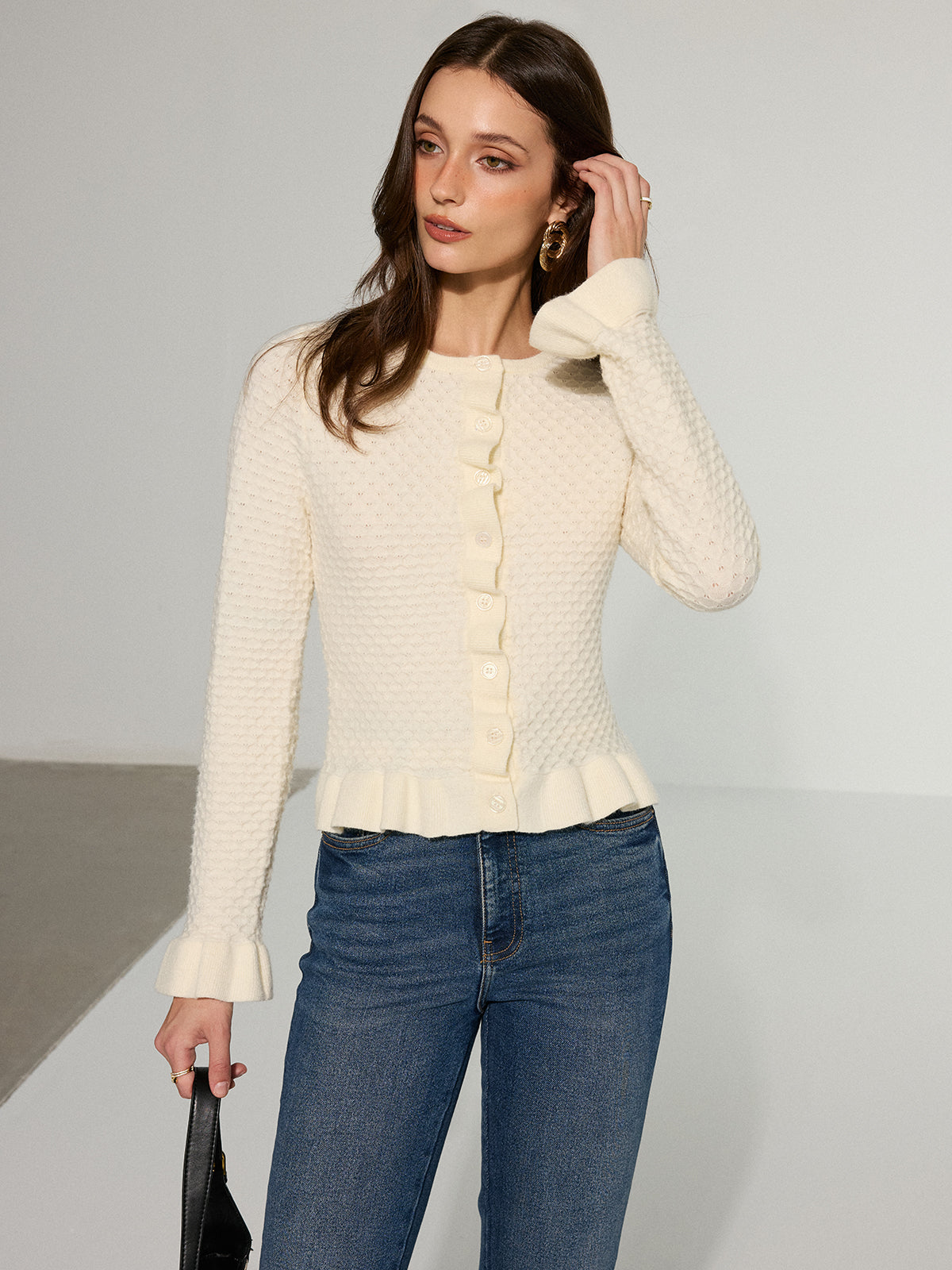 Colombe cream ruffle-hem cardigan with a black shoulder bag, angled view