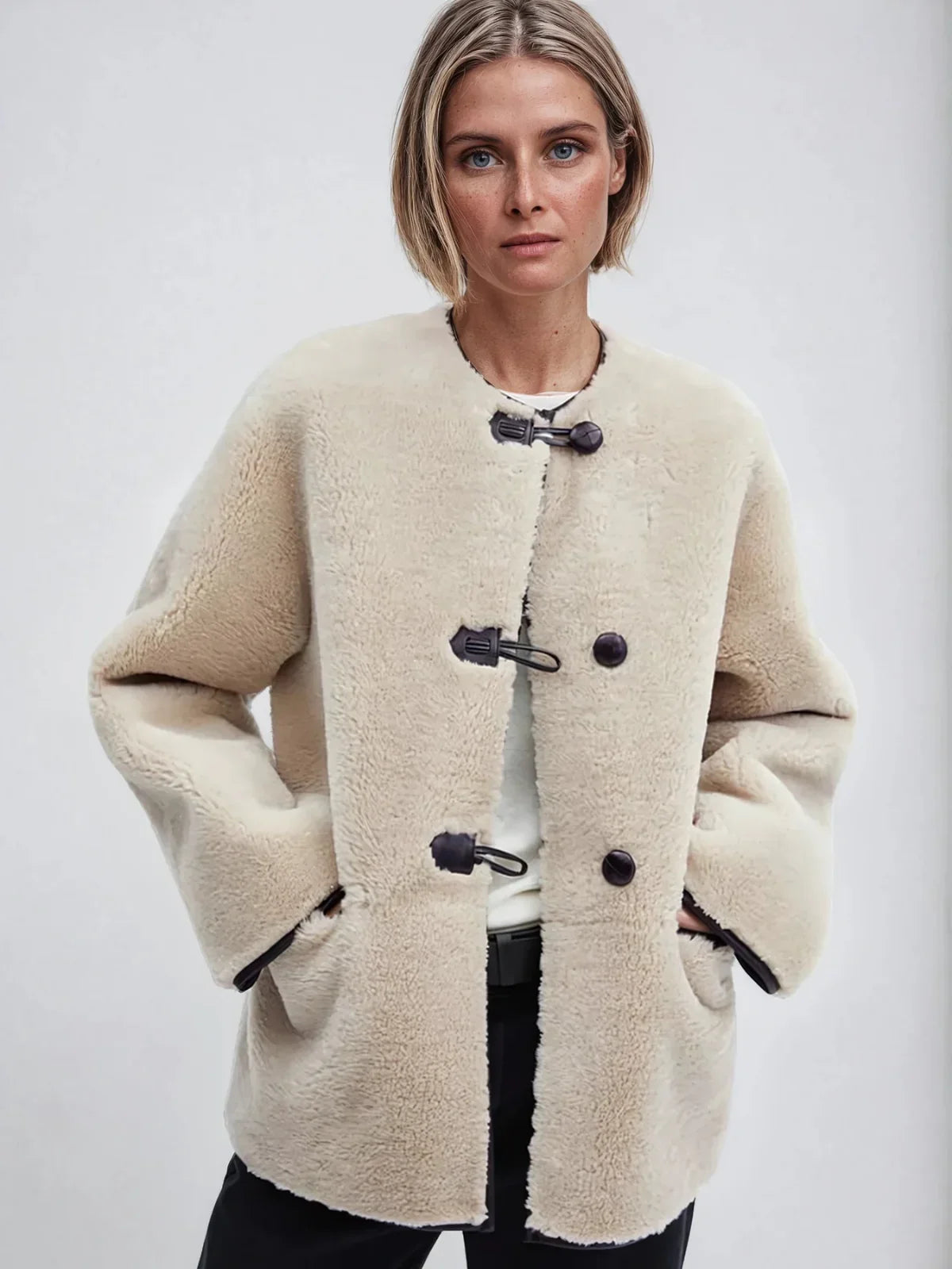 Elodie cream A-line coat with toggle clasps and hands in the pockets, front view