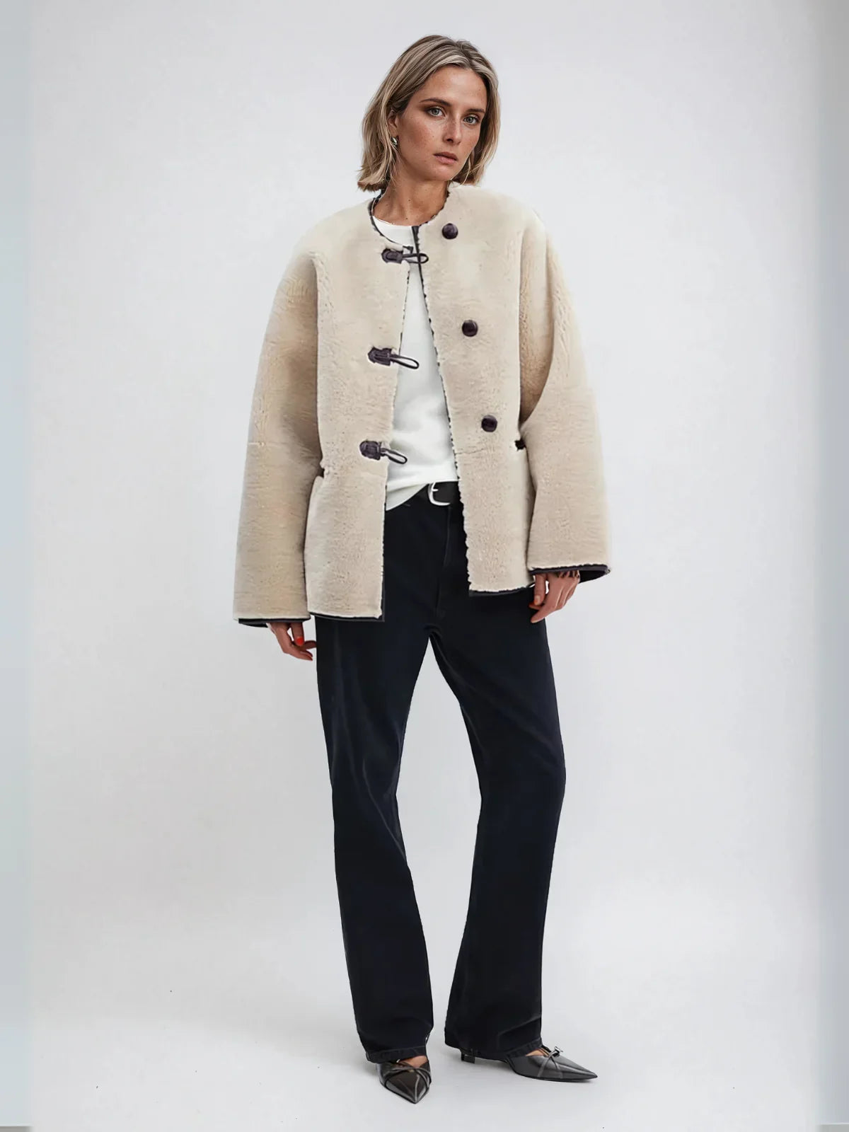 Elodie cream A-line coat worn with black trousers, full-length view