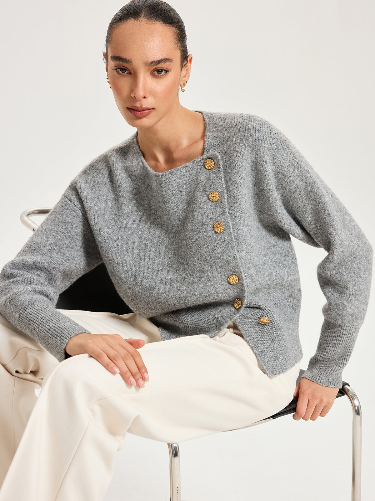 Genevieve gray asymmetric gold-button cardigan, seated three-quarter view
