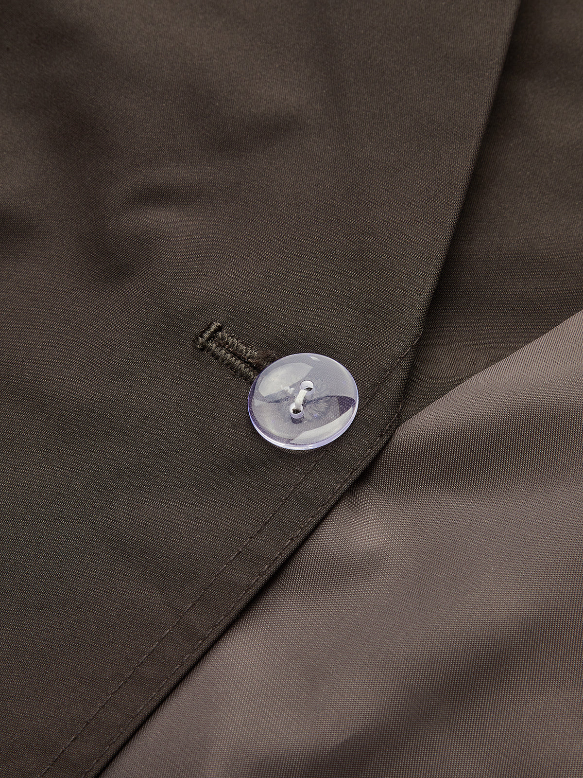 Close view of a button and lapel on a brown cropped trench jacket
