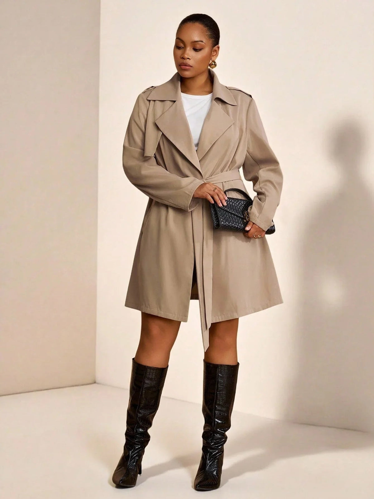 Mathilde khaki trench coat worn open over a white top and leather skirt
