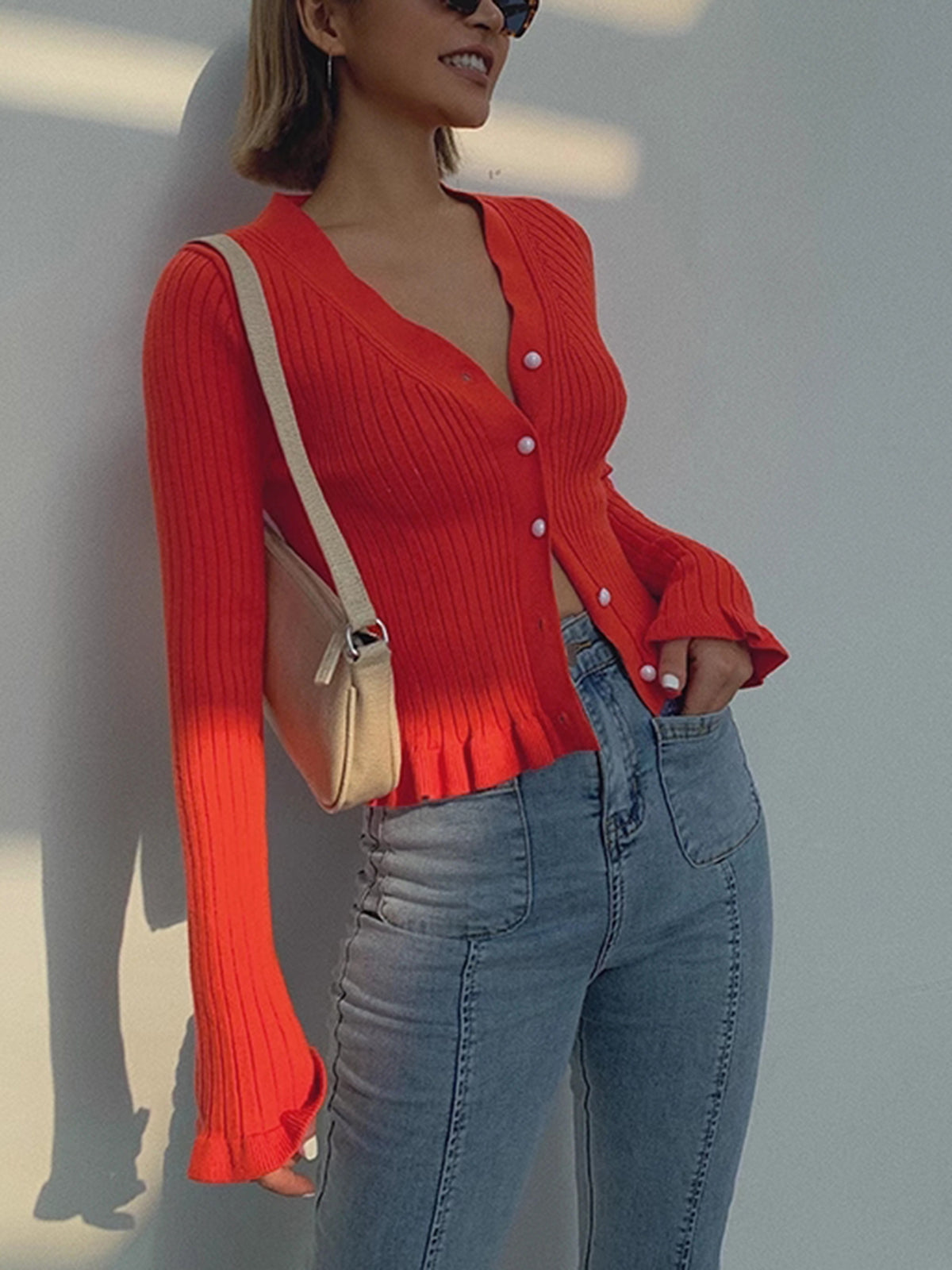 Red fitted rib cardigan showing the V neckline, white buttons and ruffled cuffs