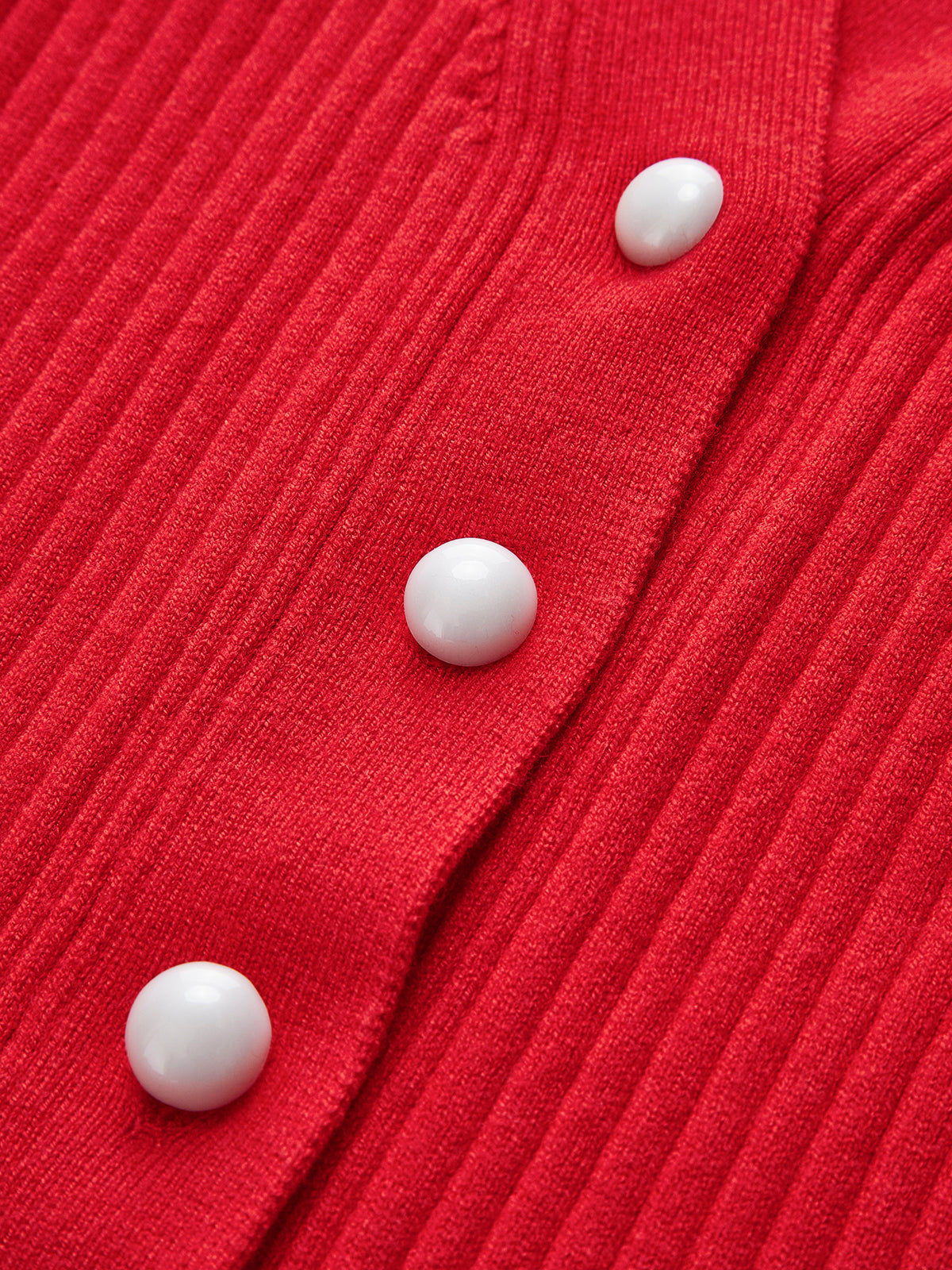 Close-up of the round white buttons on the red ribbed cardigan