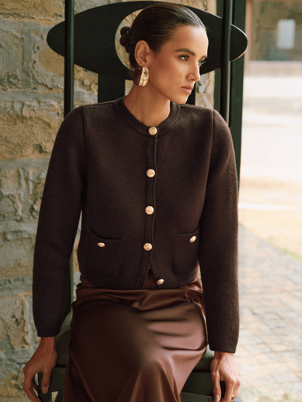 Adrienne brown gold-button cropped cardigan, seated three-quarter front view