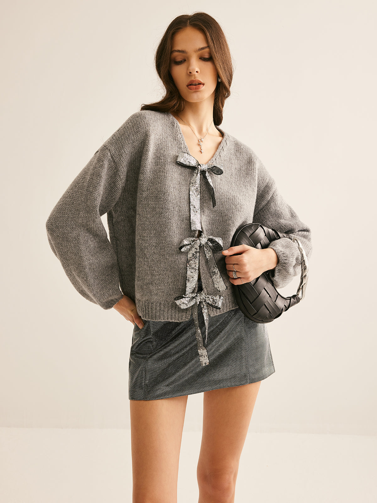 Ambre gray cardigan with deep V neckline, worn with a metallic mini skirt