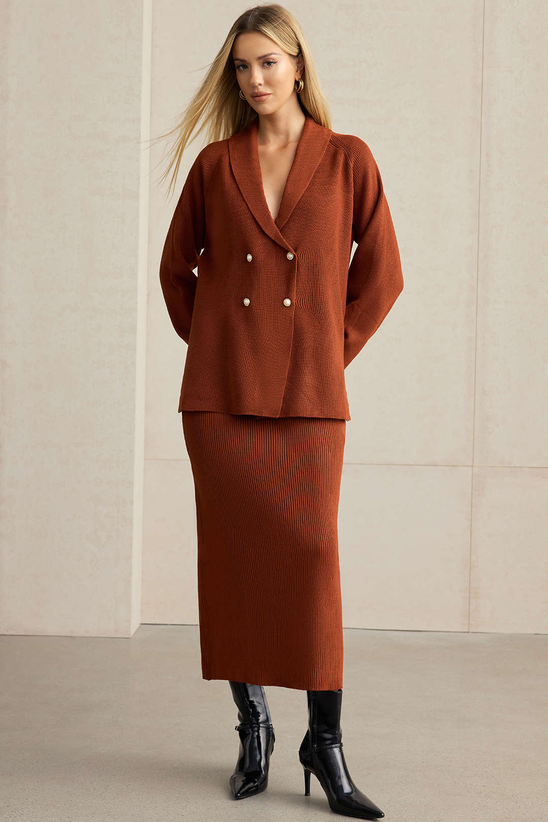 Woman wearing a rust double-breasted knit blazer with a matching ribbed midi skirt
