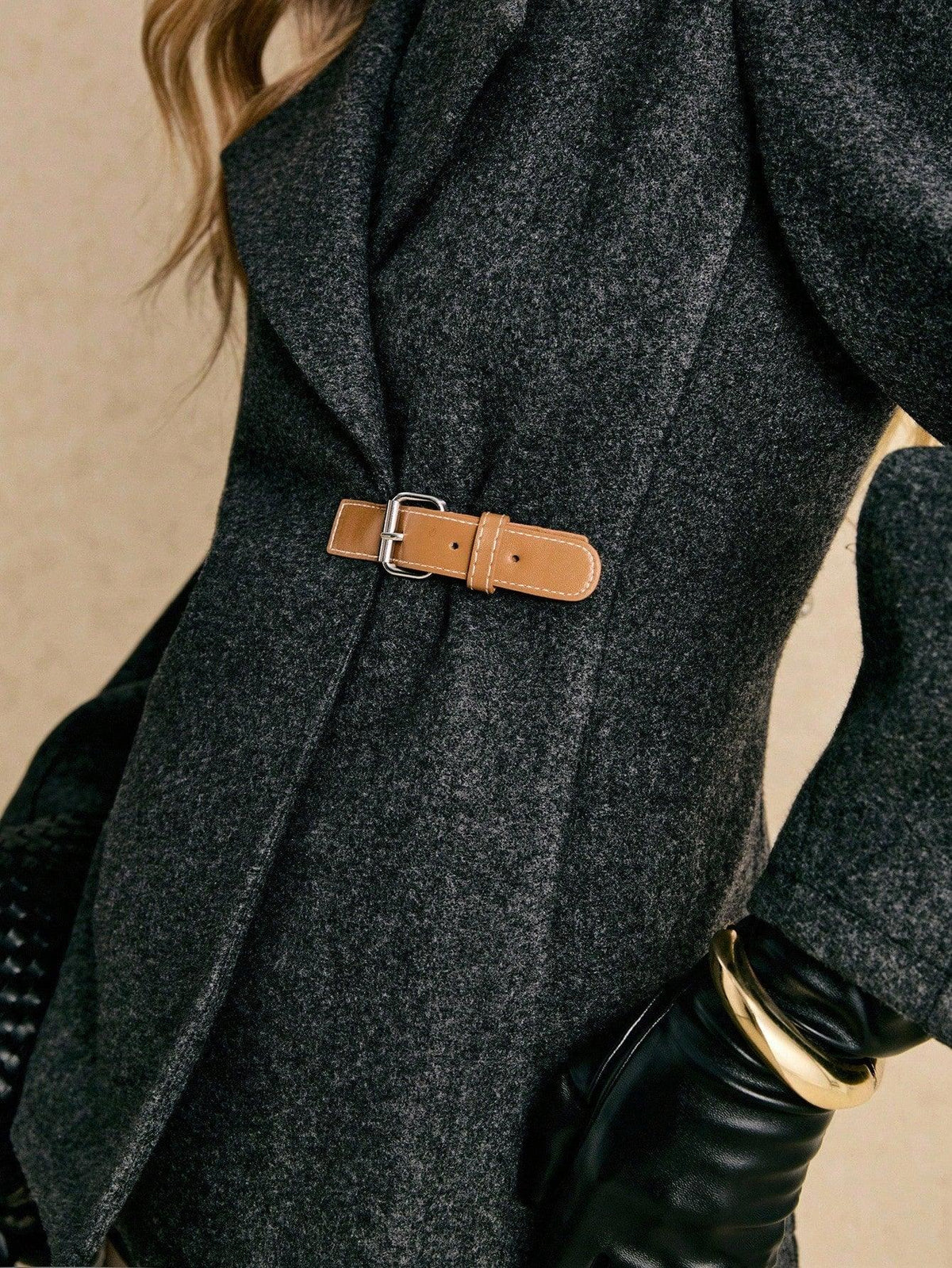 Close-up of the tan buckle belt at the waist of the Apolline coat