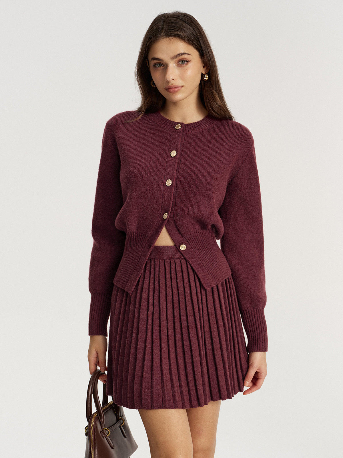 Woman wearing a burgundy button cardigan with a matching pleated knit mini skirt