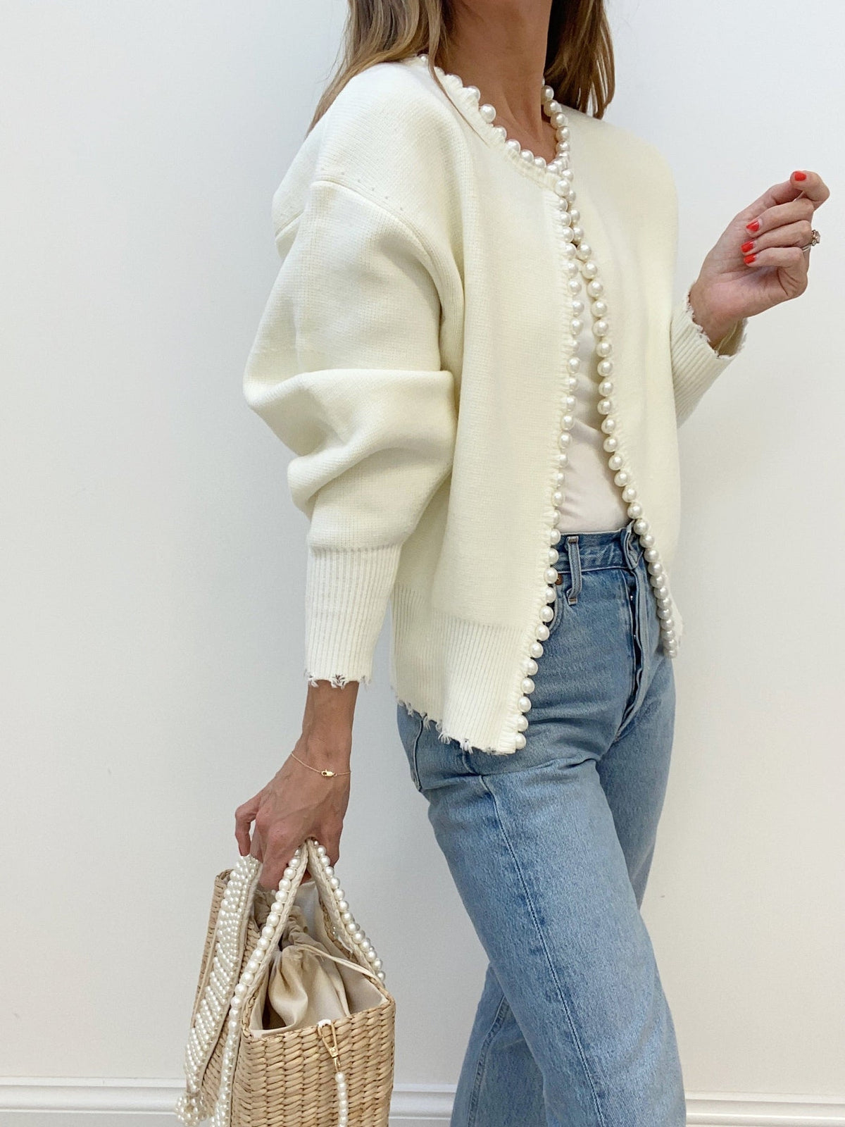 Cream pearl-edged cardigan worn open, showing the hip-length hem