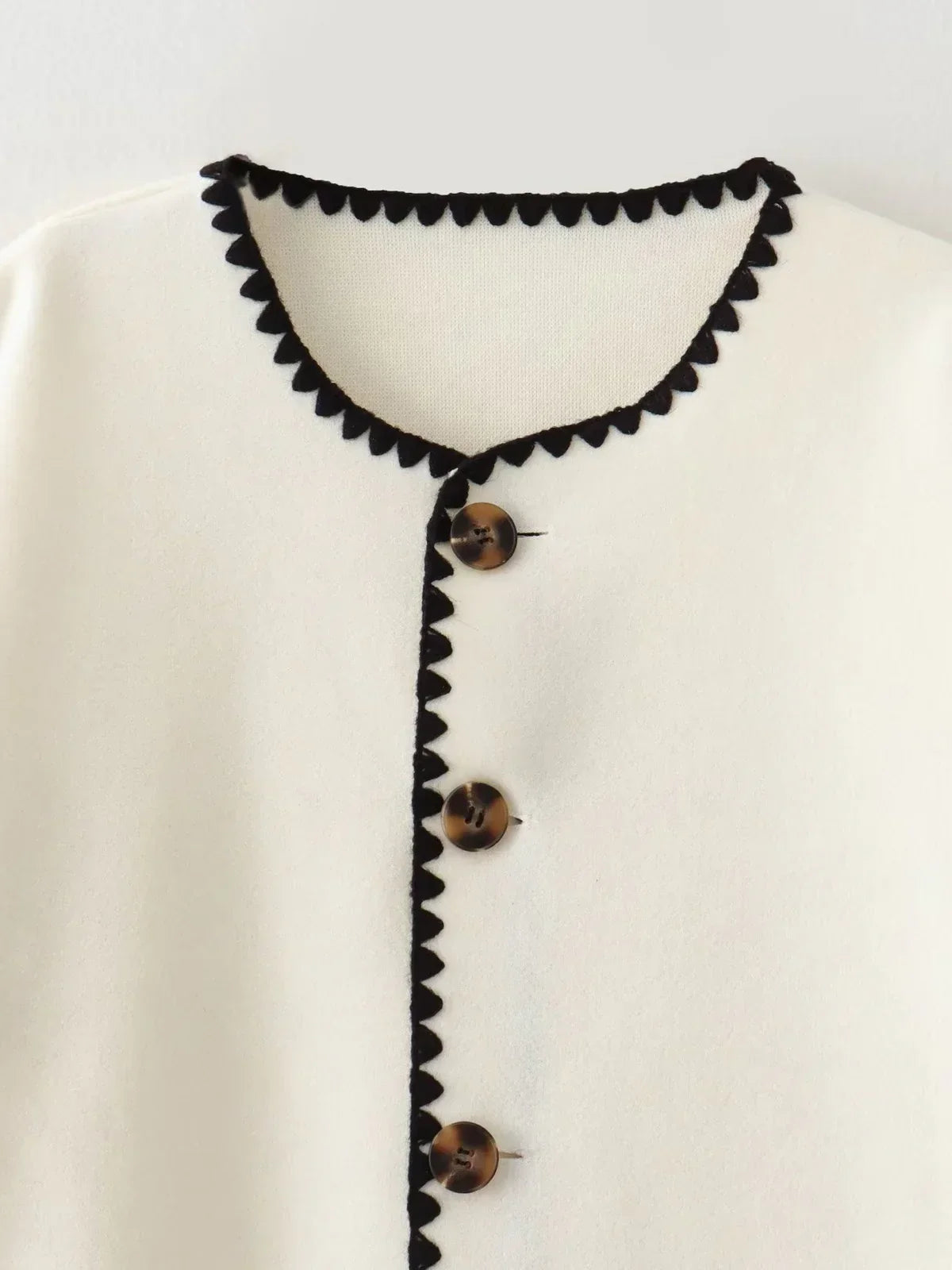 Close-up of the black blanket stitch and buttons on the Clotilde cream jacket