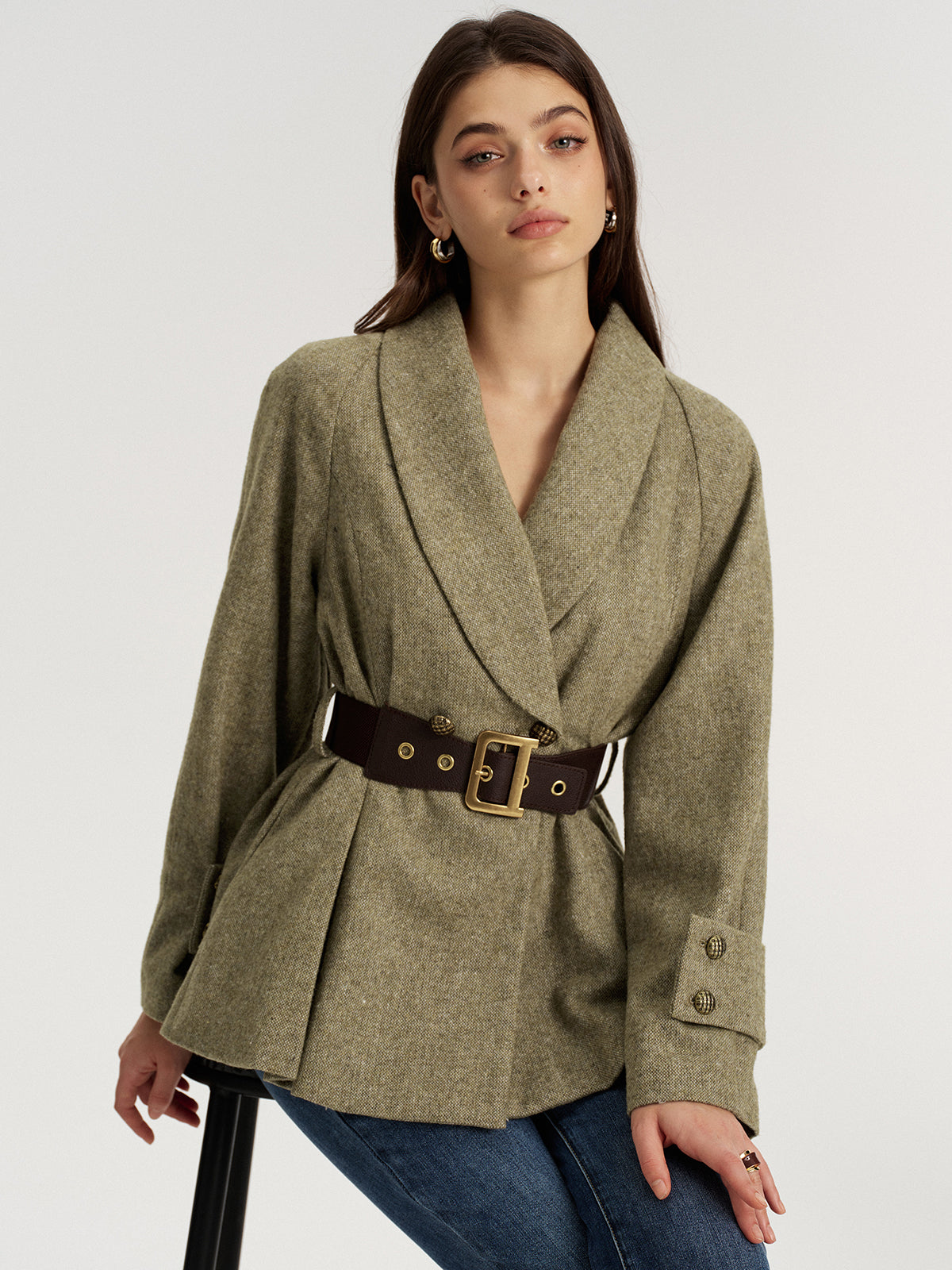 Emilienne green belted wool-blend jacket worn seated, front view with buckled waist belt