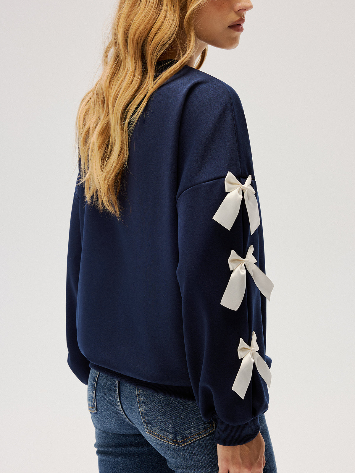 Evelyne navy ribbon bow sleeve sweatshirt, three-quarter view of three bows down one sleeve