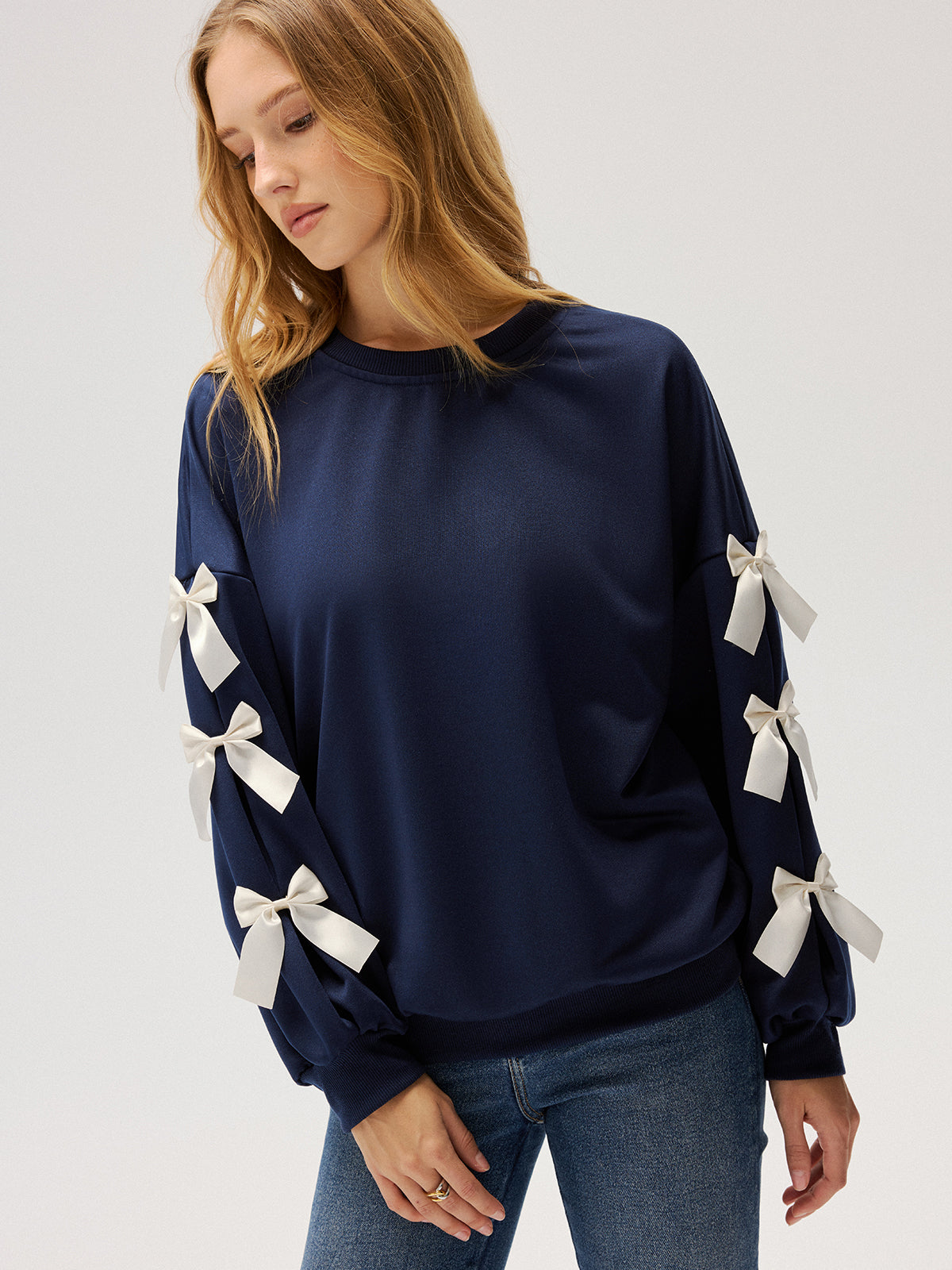 Evelyne navy ribbon bow sleeve sweatshirt, front view of the bows spaced down each arm