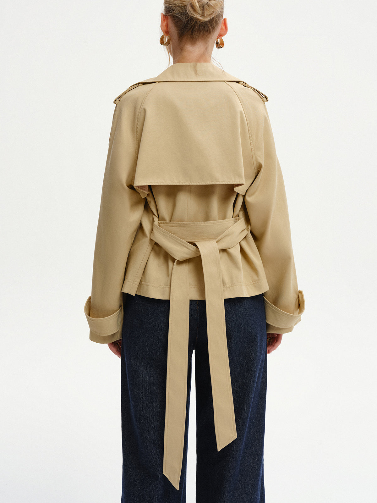 Khaki short trench coat from the back, showing the storm flap and belt