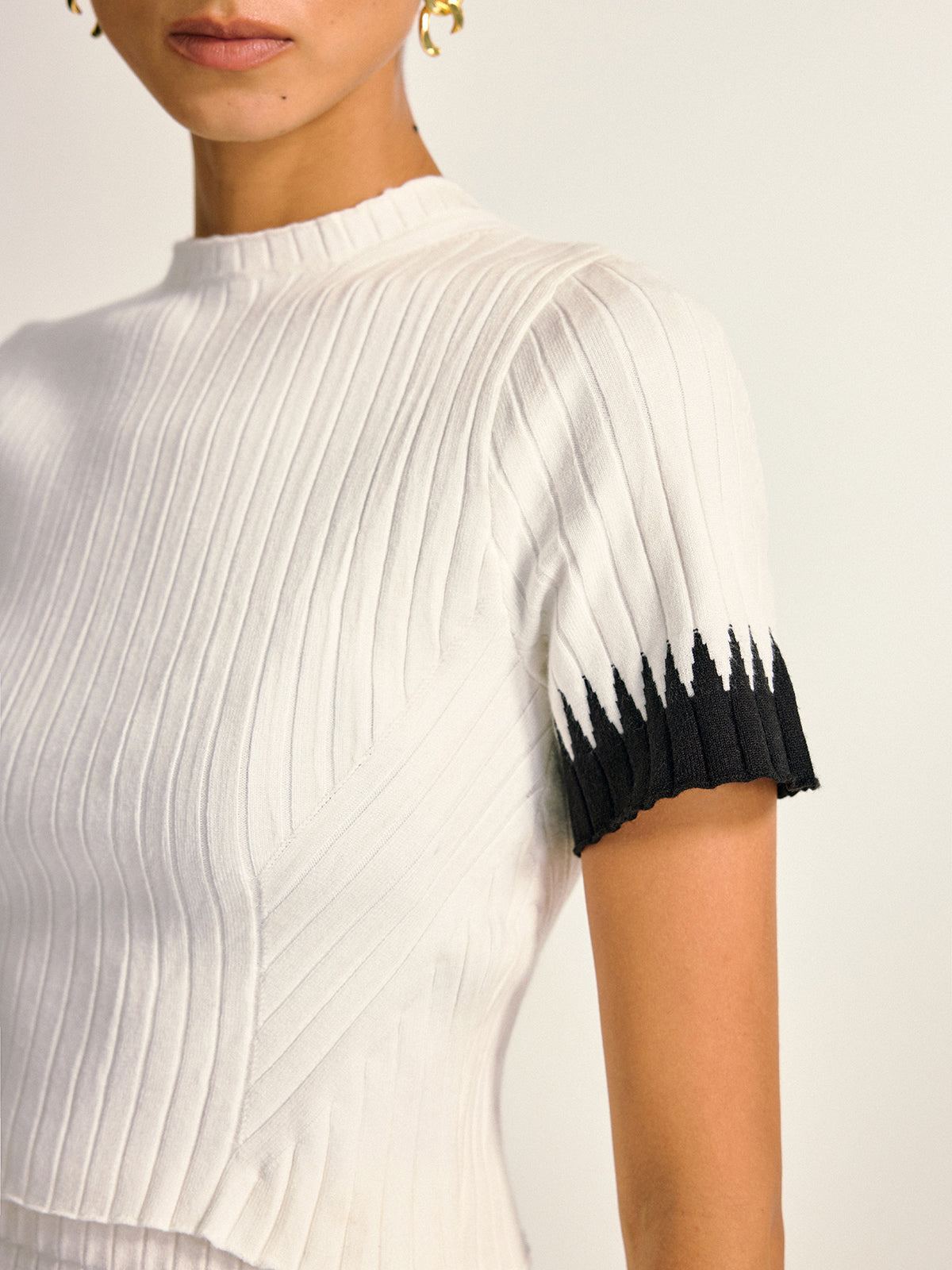 Gwenaelle white and black knit top, close-up of the mock neck and zigzag cuff