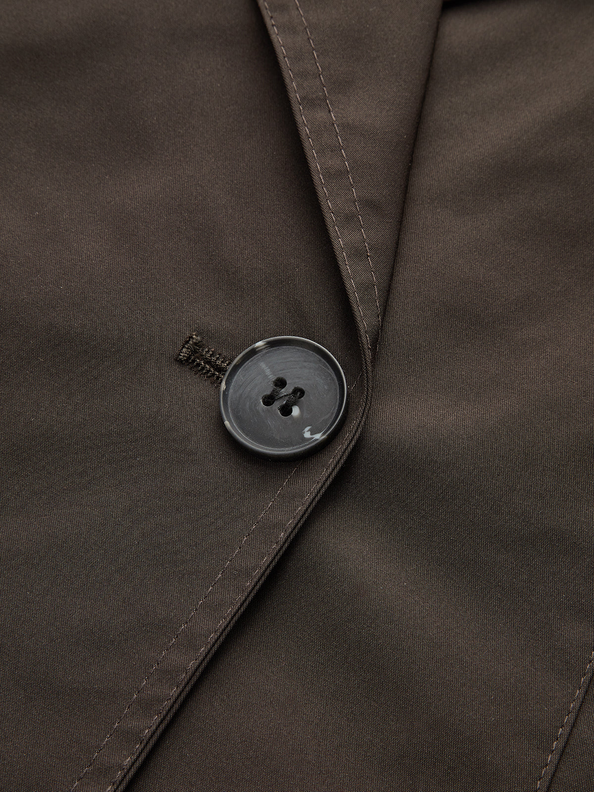 Close view of the double-breasted button fastening on a brown jacket