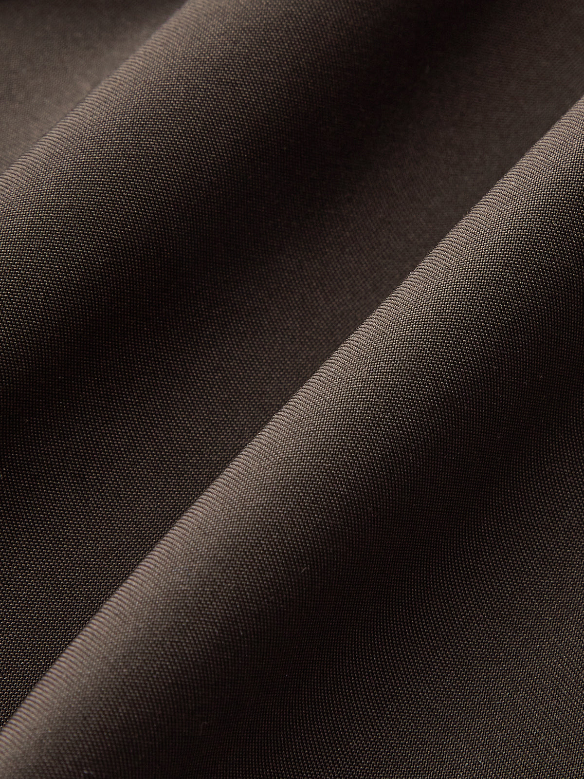 Close view of the smooth fabric surface of a brown trench jacket