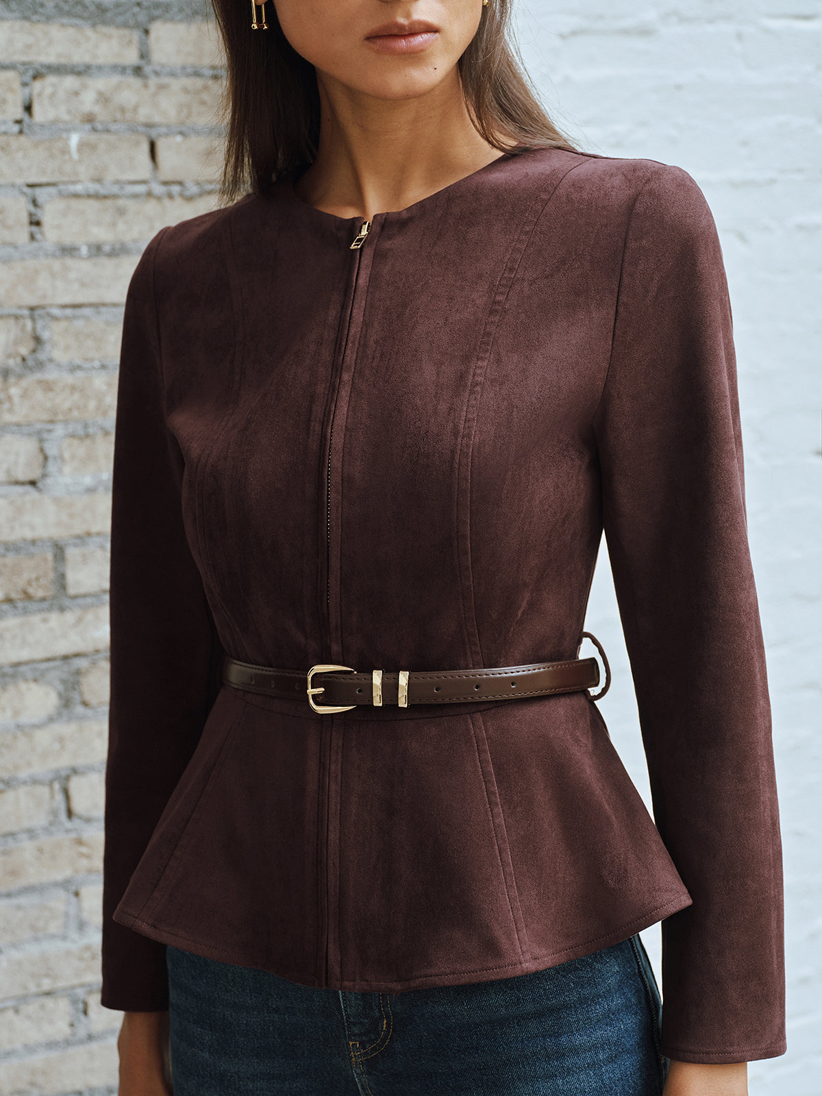 Close view of the zip front and slim belt on a brown fitted jacket