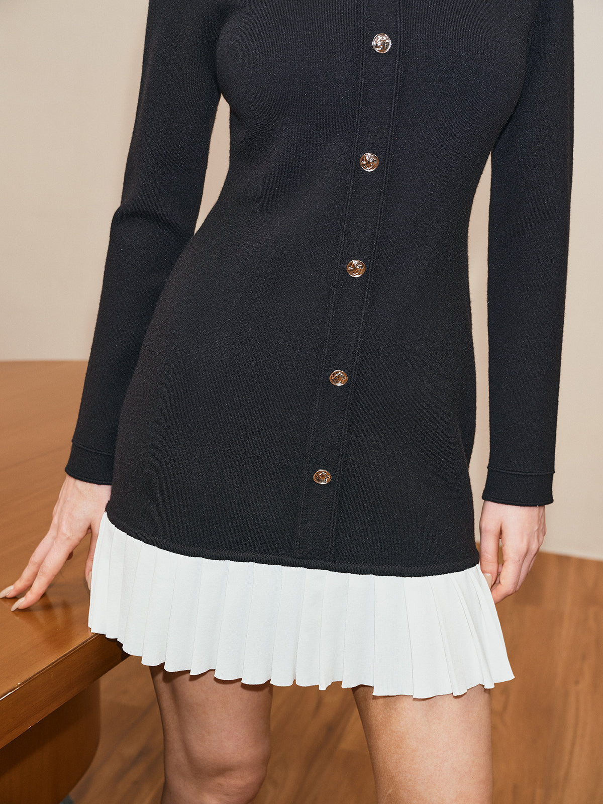 Laetitia black and white knit mini dress, close-up of the white pleated hem and gold buttons