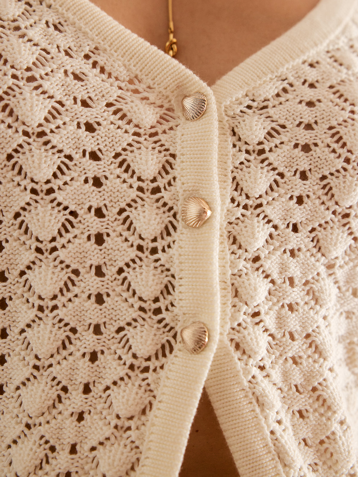 Close-up of the gold-tone buttons on the cream pointelle knit cardigan