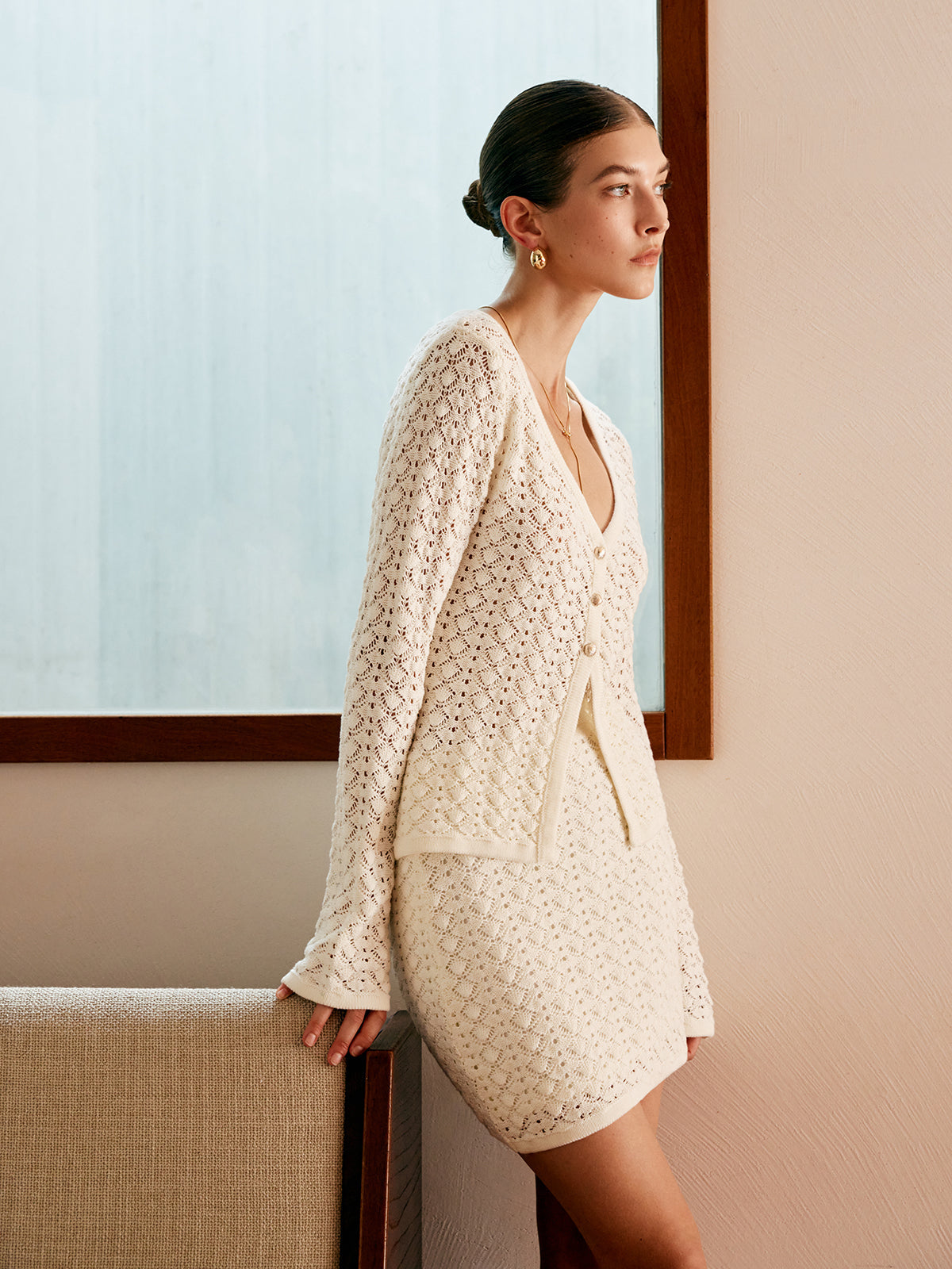 Side view of the cream openwork knit cardigan and mini skirt set