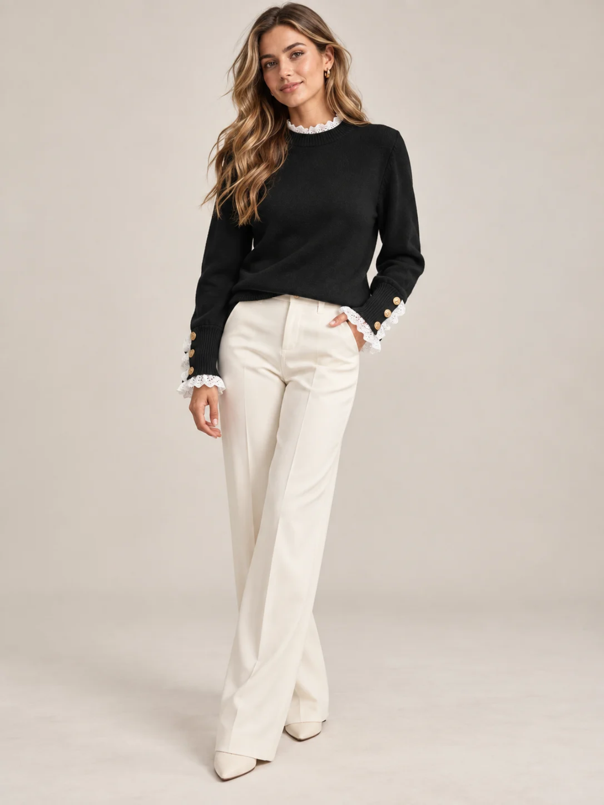 Nadine black knit sweater worn with cream trousers, full-length view