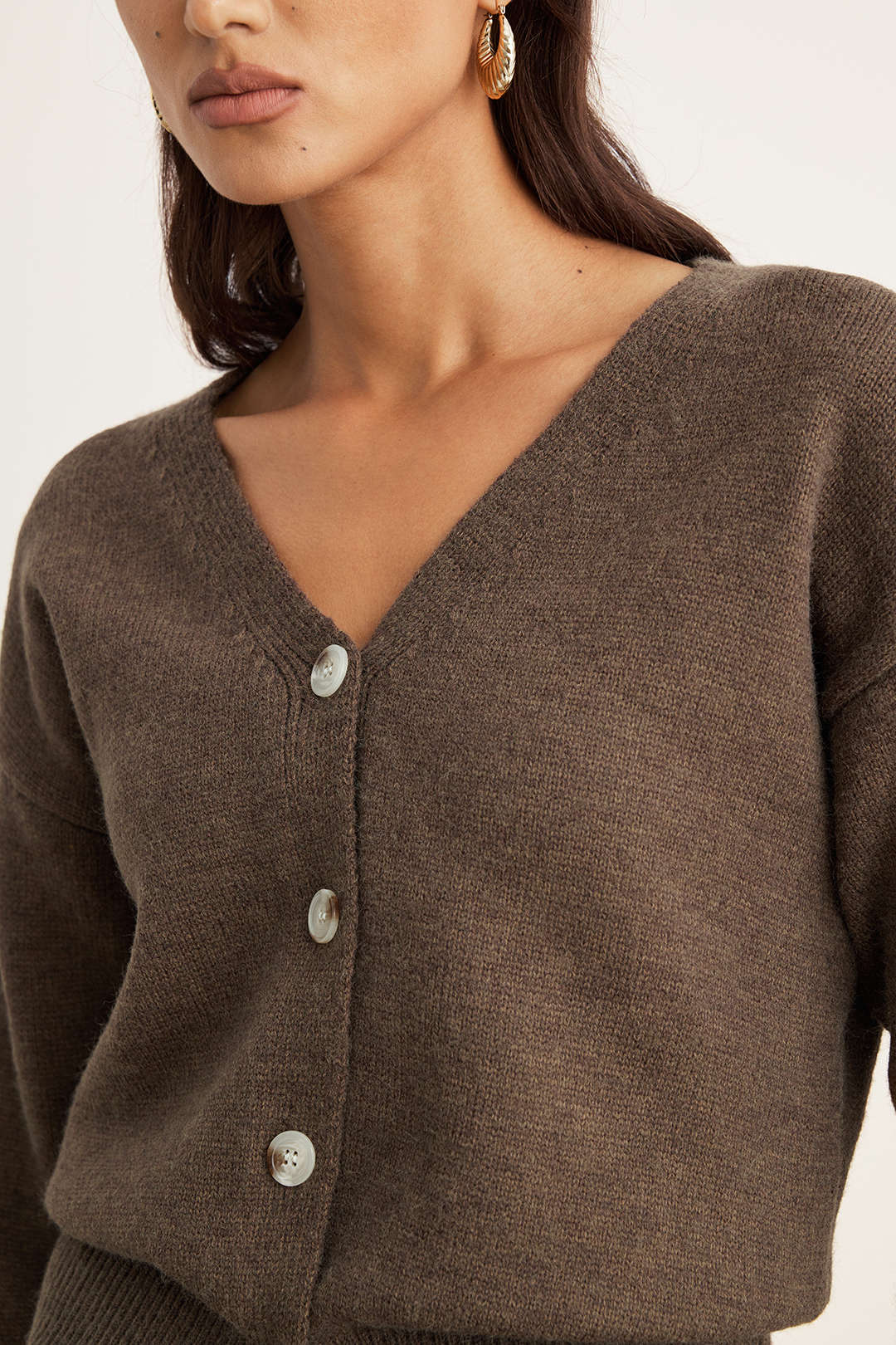 Close-up of the V neckline and buttons on the brown knit cardigan