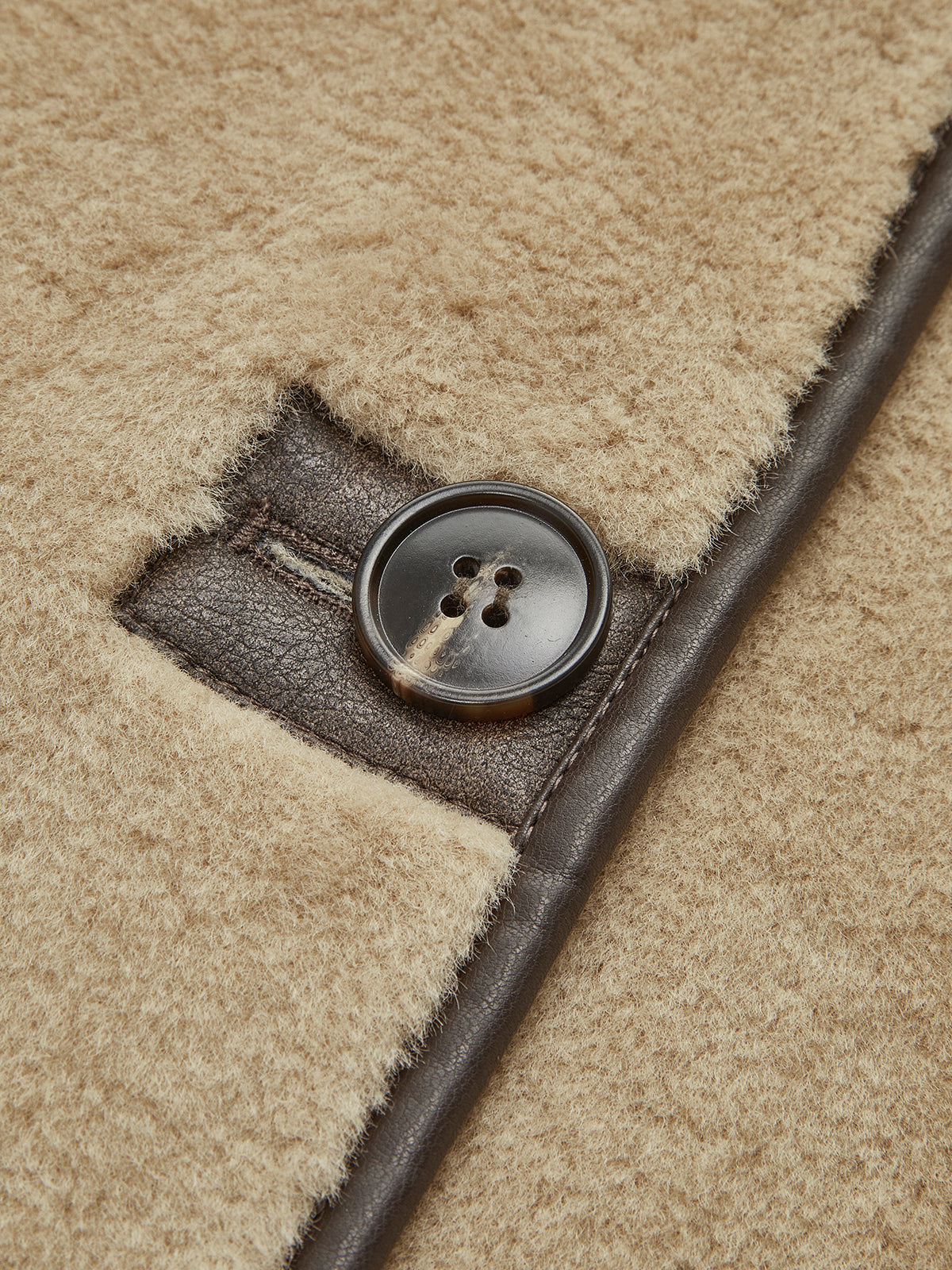 Close view of a feature button and dark contrast trim on a beige jacket