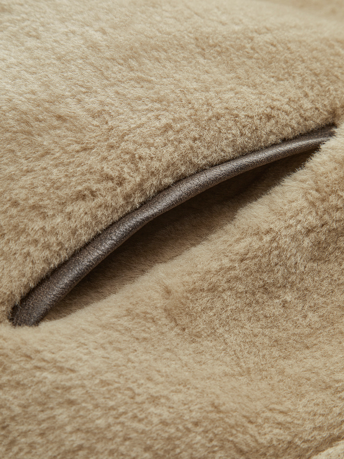 Close view of the deep-pile surface and dark piped edge of a beige jacket