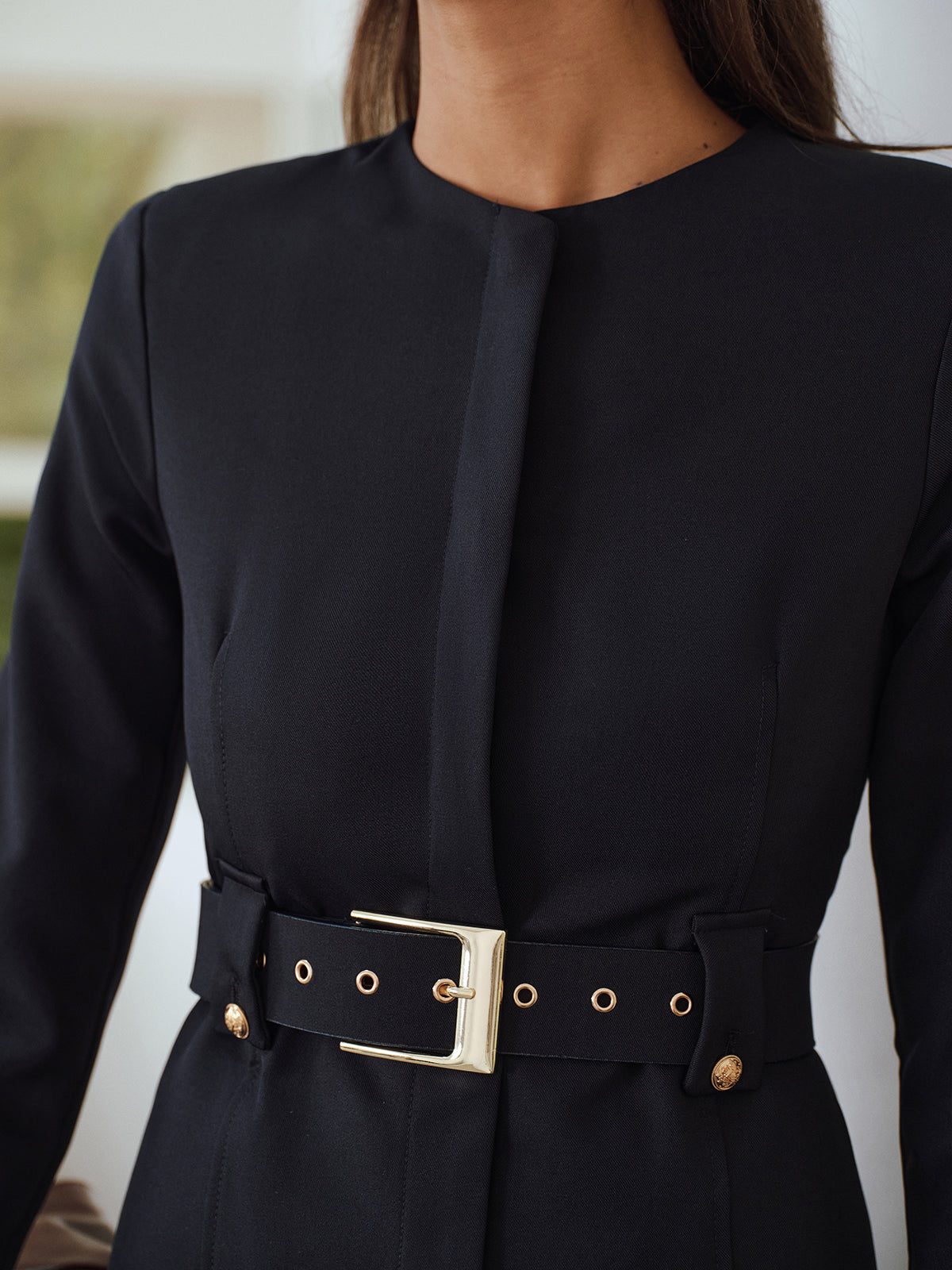 Close view of the wide belt and oversized buckle on a navy blue jacket