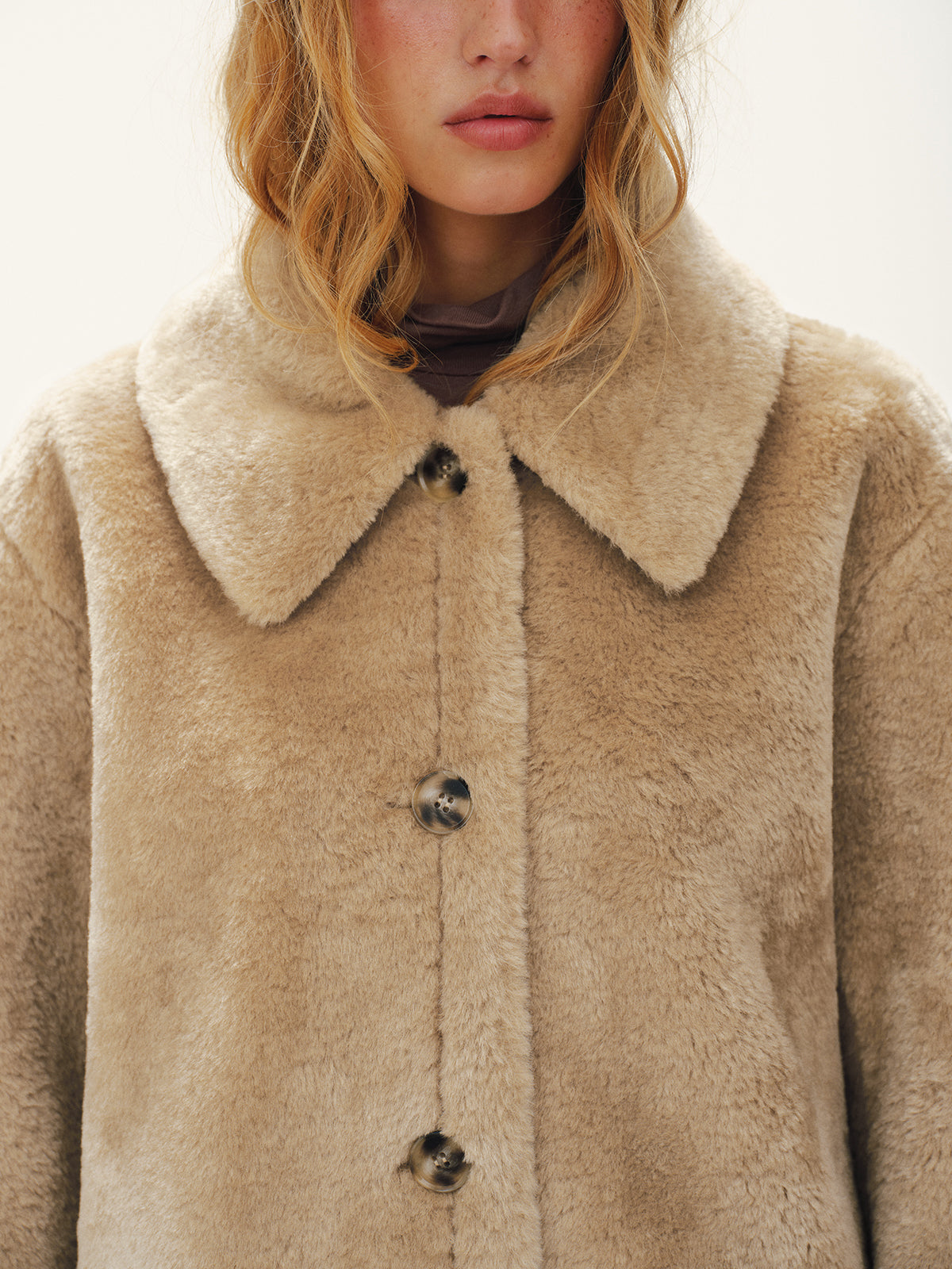 Close view of the soft oversized collar and buttons on a beige plush jacket