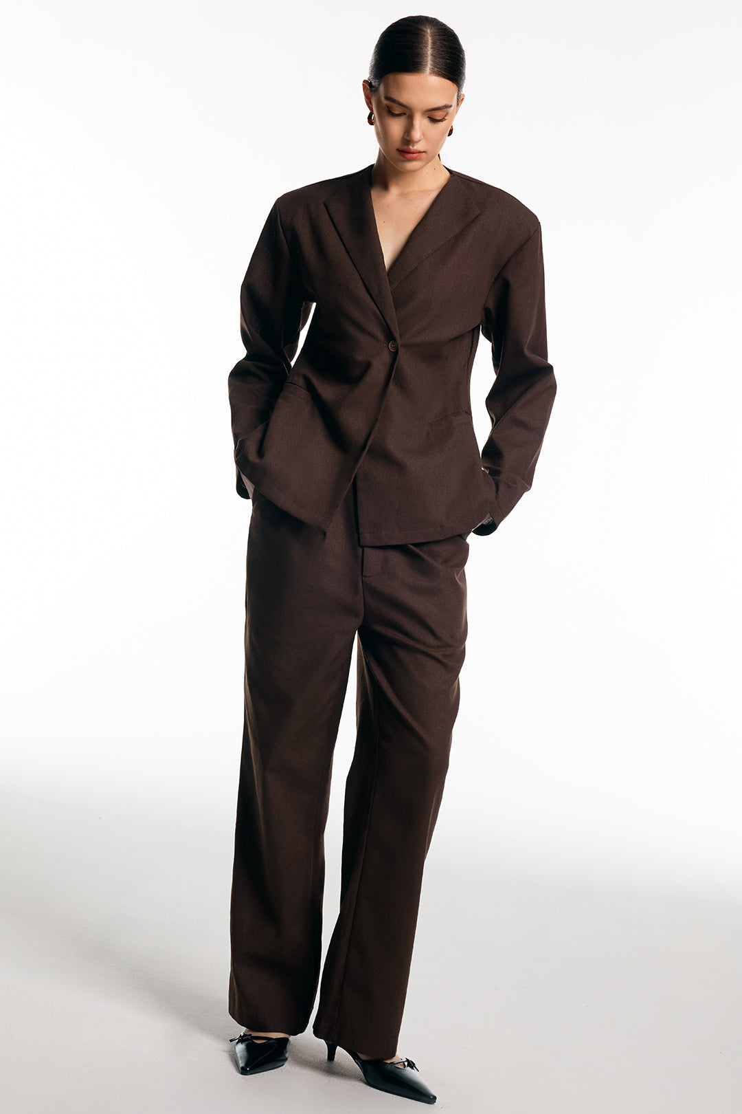 Woman wearing a chocolate brown single-button blazer with matching straight-leg trousers