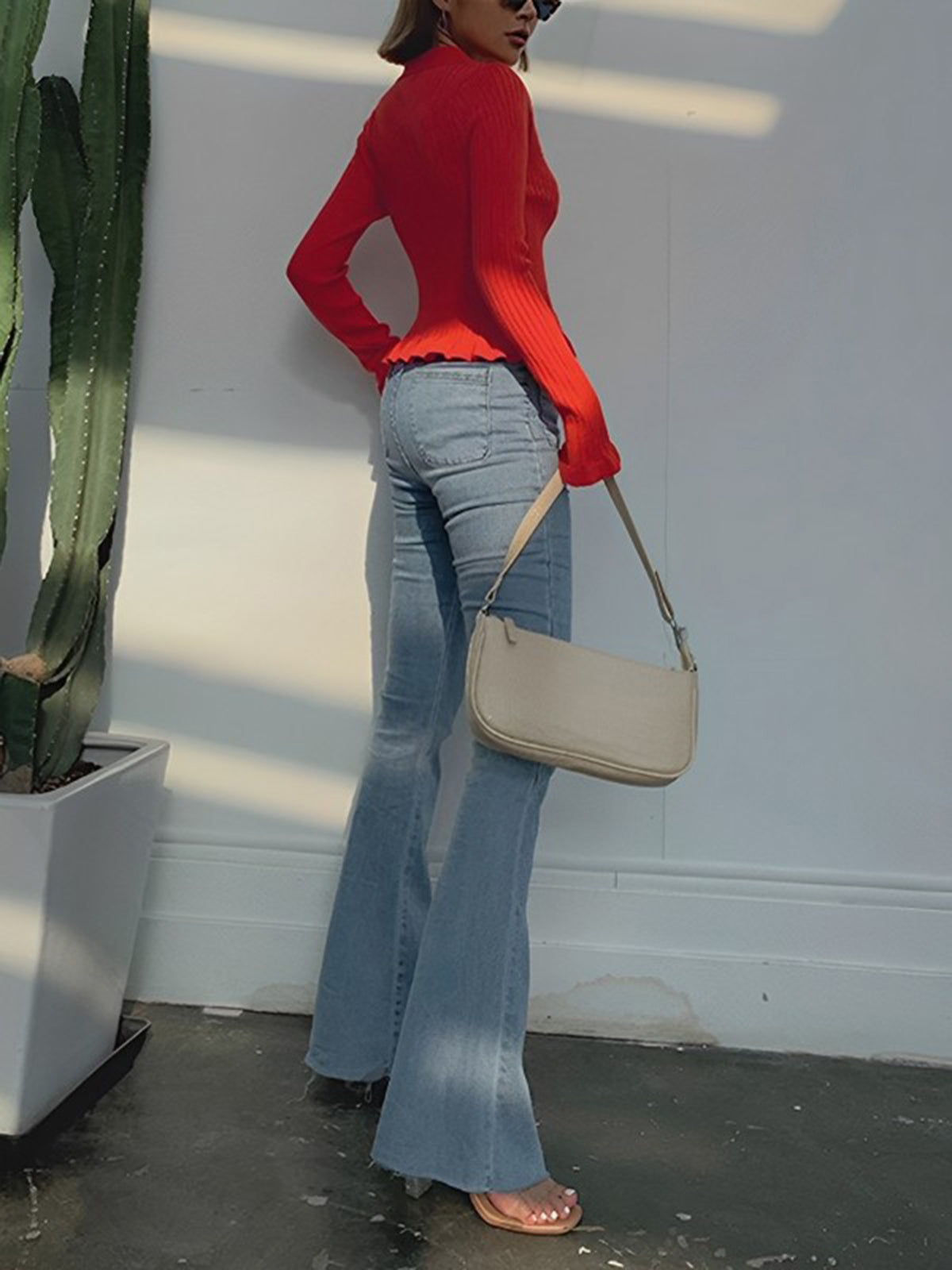 Back view of the red ribbed cardigan showing the ruffled waist-length hem