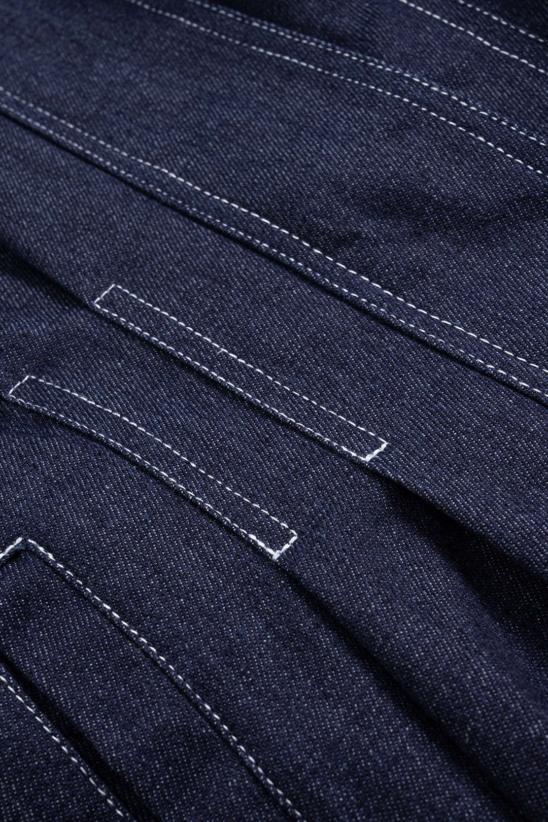 Violette navy denim jacket, close-up of the contrast stitching and belt loops